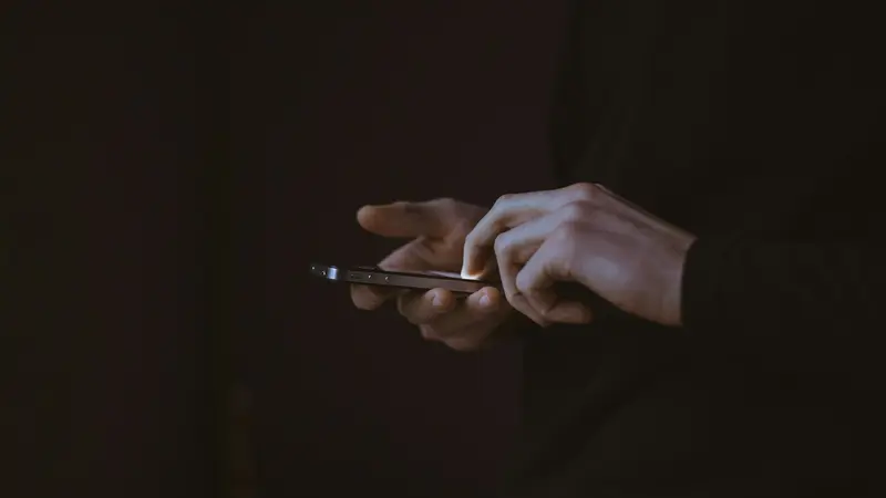 Una persona al buio che scorre lo smartphone