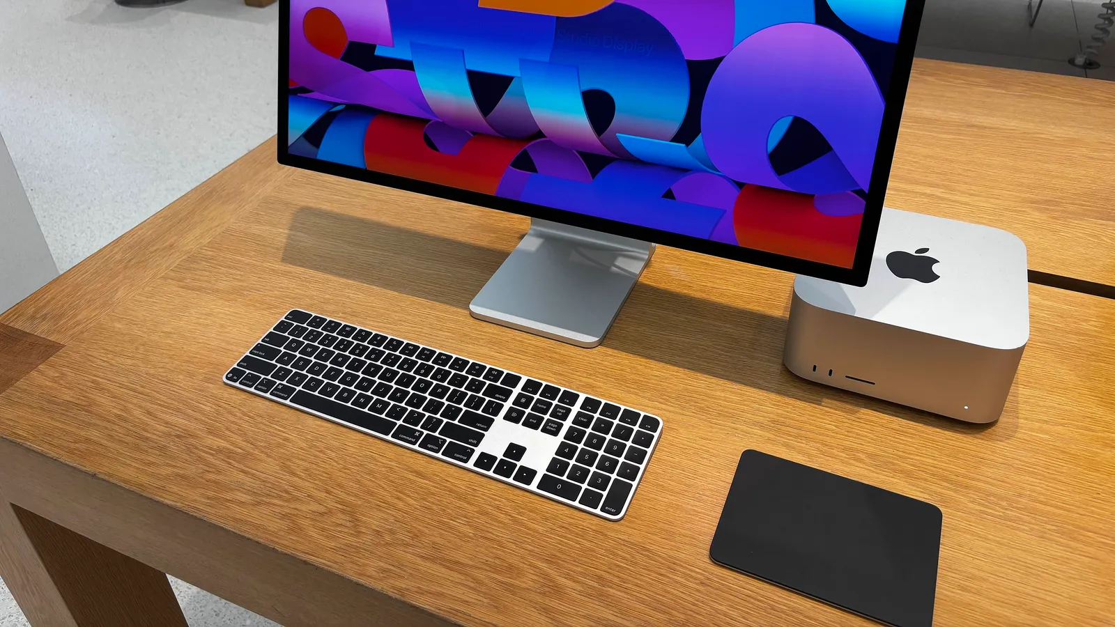 Un Mac Studio con monitor, tastiera e trackpad su una scrivania di legno